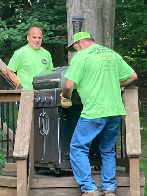 two workers lifting a bbq appliance